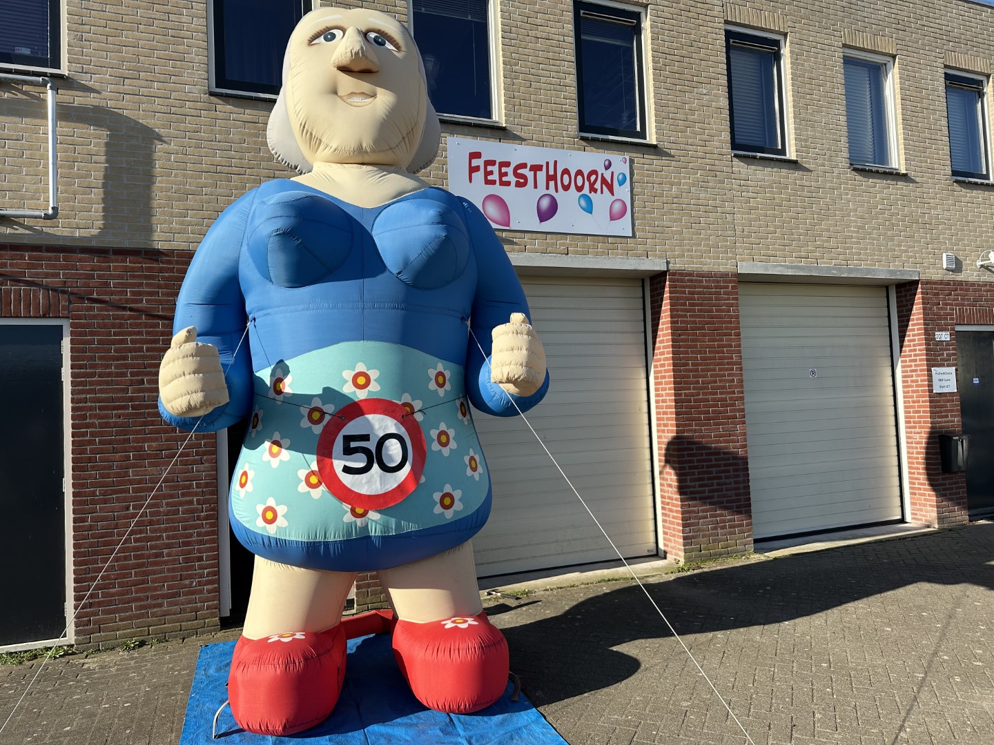 De opblaasbare Sarah XL pop van 4,2 meter hoog met de duimen omhoog. Geleverd met een verkeersbordbanner naar keuze of een 'pensioen' banner.